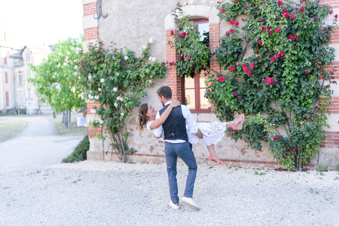 Un marié qui porte sa femme le jour de leur mariage À la flèche
